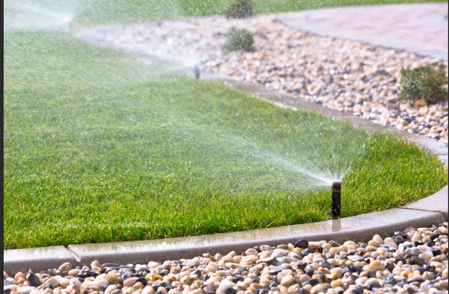 Pop-up rotor sprinkler delivering precision watering on a residential lawn with decorative gravel border
